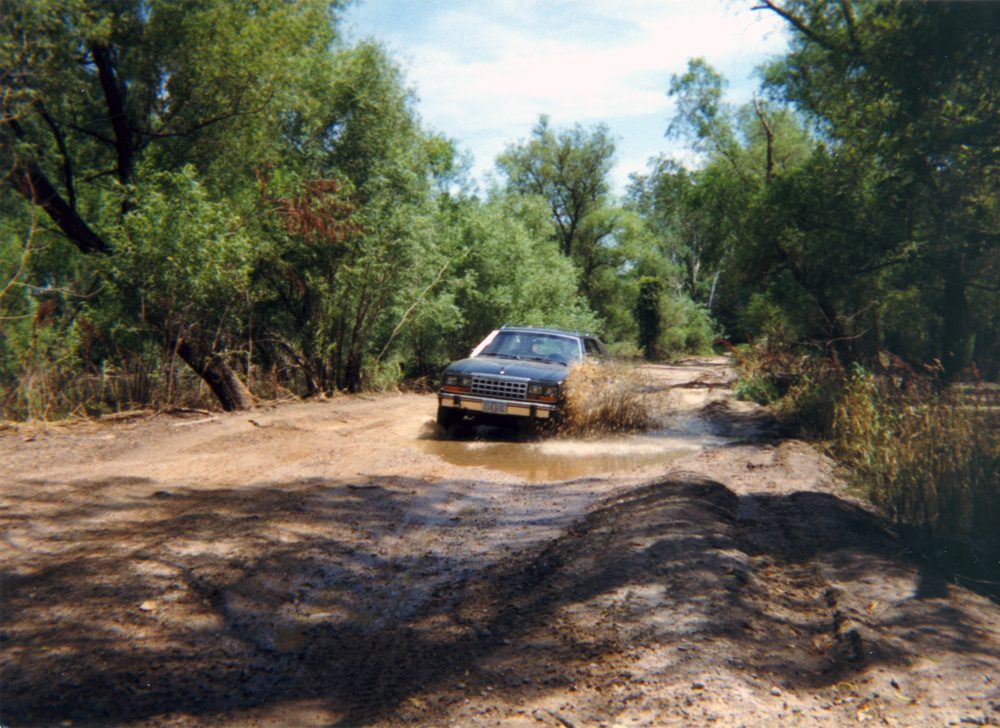 An Eagle wagon splashing through a muddy water crossing on a dirt trail